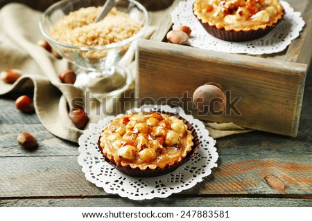 Mini cakes with nuts on napkin on wooden background