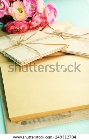 Old letters and book with flowers on wooden background
