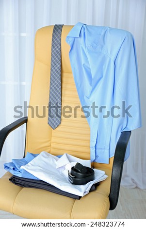 Men\'s clothes on chair with curtain on background