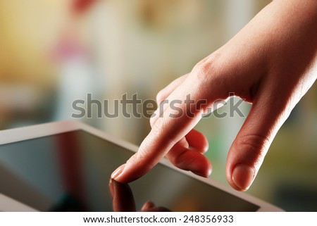 Hand using tablet PC on wooden table and light blurred background
