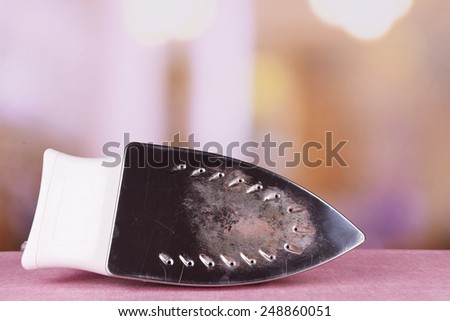 Flat iron with burnt mark on table on bright background