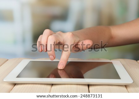 Hand using tablet PC on wooden table and light blurred background