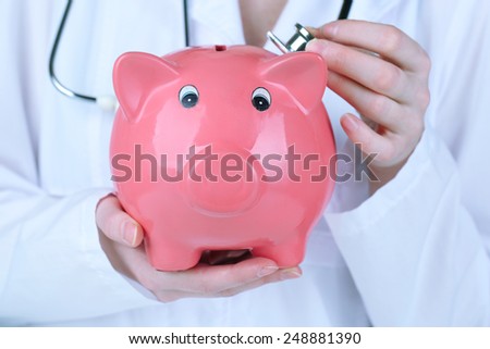 Doctor with pink piggy bank, close up