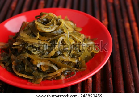 Seaweed in red bowl on bamboo mat background