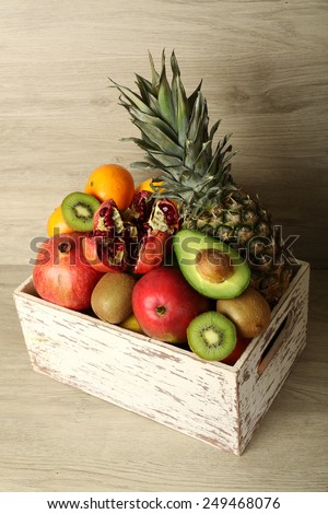 Assortment of exotic fruits in box on wooden background