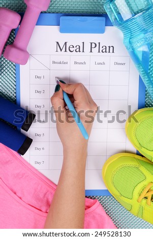 Sports trainer amounts to meal plan and sports equipment top view close-up