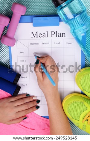 Sports trainer amounts to meal plan and sports equipment top view close-up