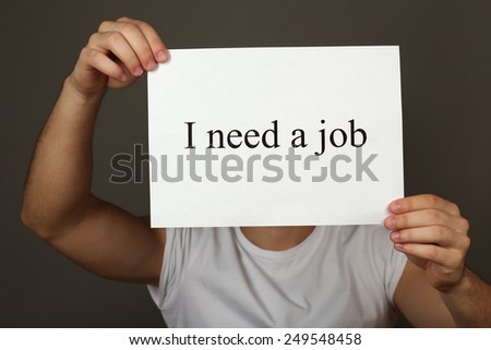 Sheet of paper with inscription I need a job in male hands on dark background