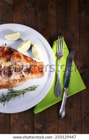 Dish of Pangasius fillet with spices and vegetables on plate and wooden table background