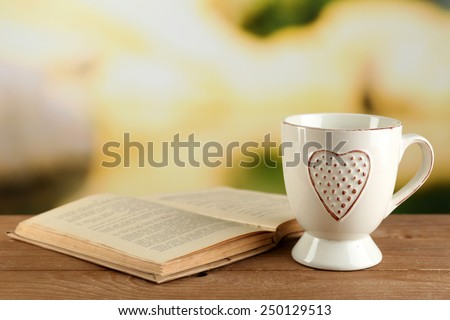 Cup of tea and book on table, on bright background