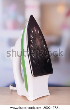Flat iron with burnt mark on table on bright background