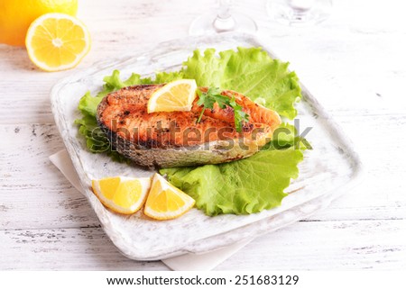 Tasty baked fish on plate on table close-up