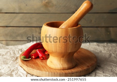 Ground red pepper in mortar with chili pepper on wooden background