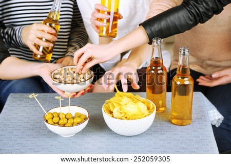 Friends hands with bottles of beer and snacks, close up