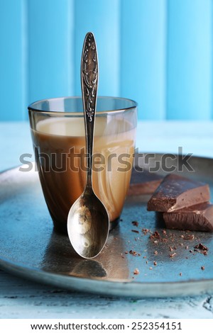 Glass of milk with chocolate chunks on metal tray and color wooden planks background