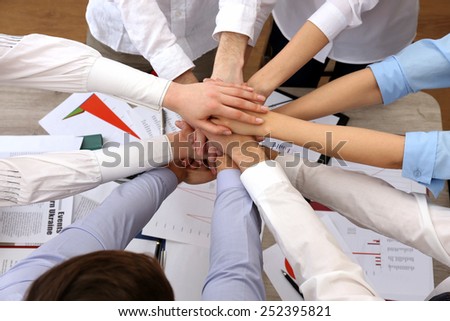 United hands of business team on workspace background top view
