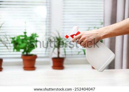 Male hand with sprayer wash windowsill on window background