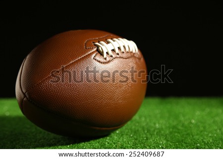American football on green grass, on black background