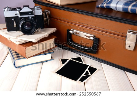 Vintage suitcase with clothes and books on table on dark background