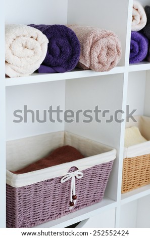 Rolled towels with wicker baskets on shelf of rack background