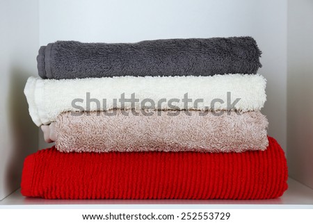 Colorful towels on shelf of rack background