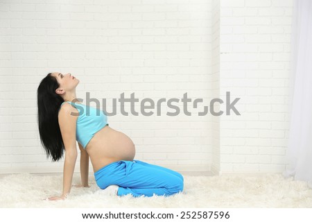 Young pregnant woman on light background. Yoga for pregnant women concept