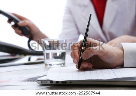 Signing of documents at worktable on white blurred background