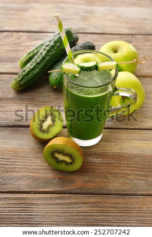 Green fresh healthy juice with fruits and vegetables on wooden table background