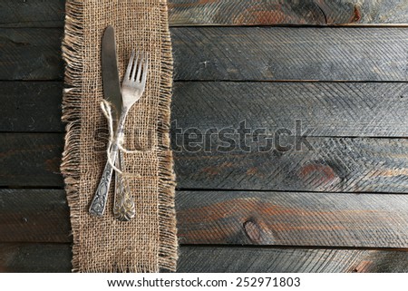 Silverware tied with rope on burlap cloth and wooden planks background