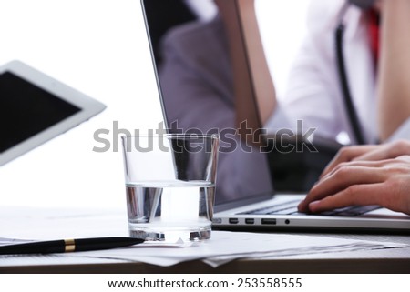 Working with laptop at worktable on white blurred background