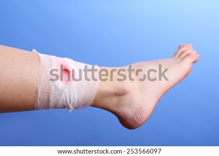 Wounded leg with bandage on blue background
