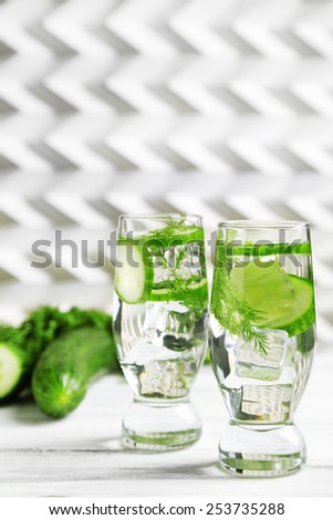 Glasses with fresh organic cucumber water on wooden table, on light background