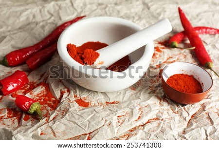 Ground red pepper in mortar with chili pepper on table close up