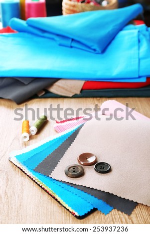 Colorful fabric samples with buttons and threads on wooden table background