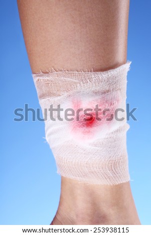 Wounded leg with bandage on blue background