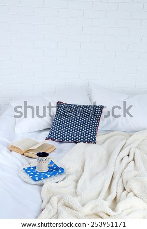 Book and cup of tea on bed close-up