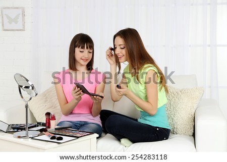 Two girls  with decorative cosmetics on home interior background