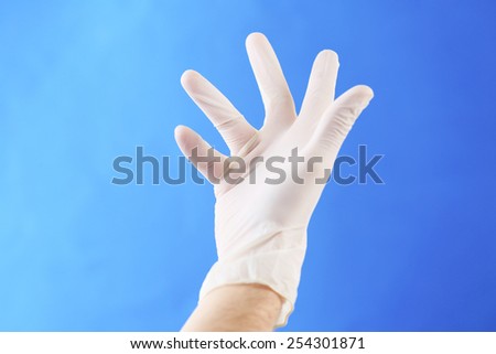 Doctor hand in sterile gloves on blue background