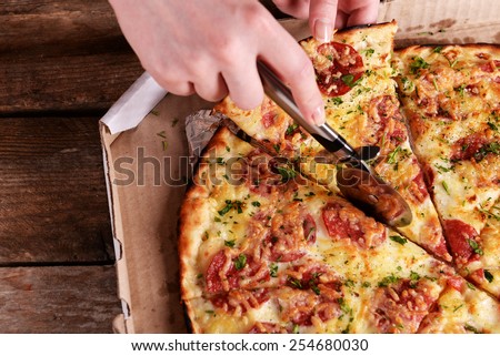 Girl cut pizza on table close up