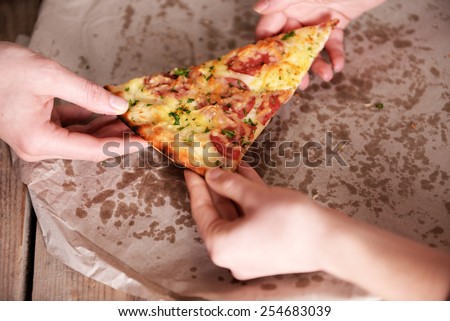 Friends hands taking slice of pizza