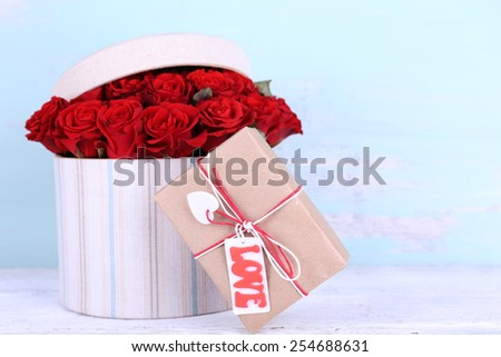 Bouquet of red roses in textile box with present on wooden background