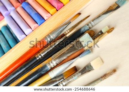 Paintbrushes with colorful chalk pastels in box on fabric background