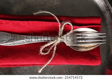 Silverware tied with rope on red napkin and metal tray background