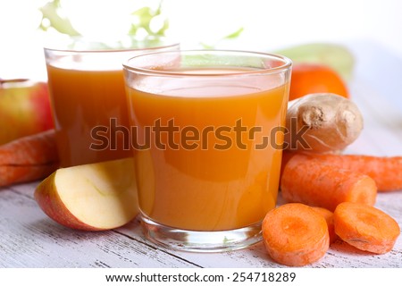 Glasses of juice with apple and carrot on wooden table close up