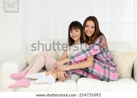 Two girls in pajamas sitting on sofa