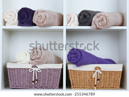 Rolled towels with wicker basket son shelf of rack background