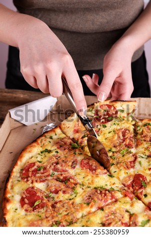 Girl cut pizza on table close up