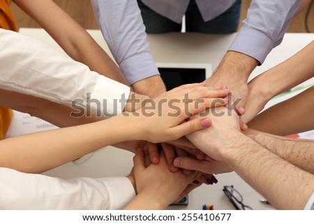 United hands of business team on workspace background top view
