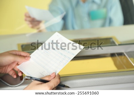 Teller window with working cashier and female hands with claim check. Concept of payment of utilities