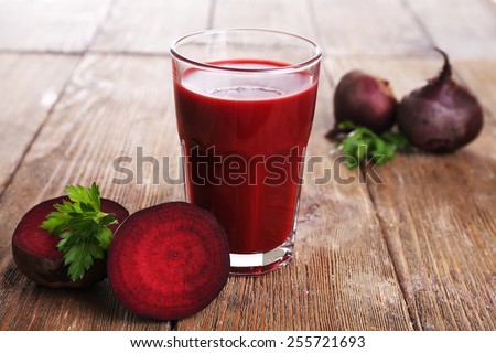 Glass of beet juice with beets on wooden table close up